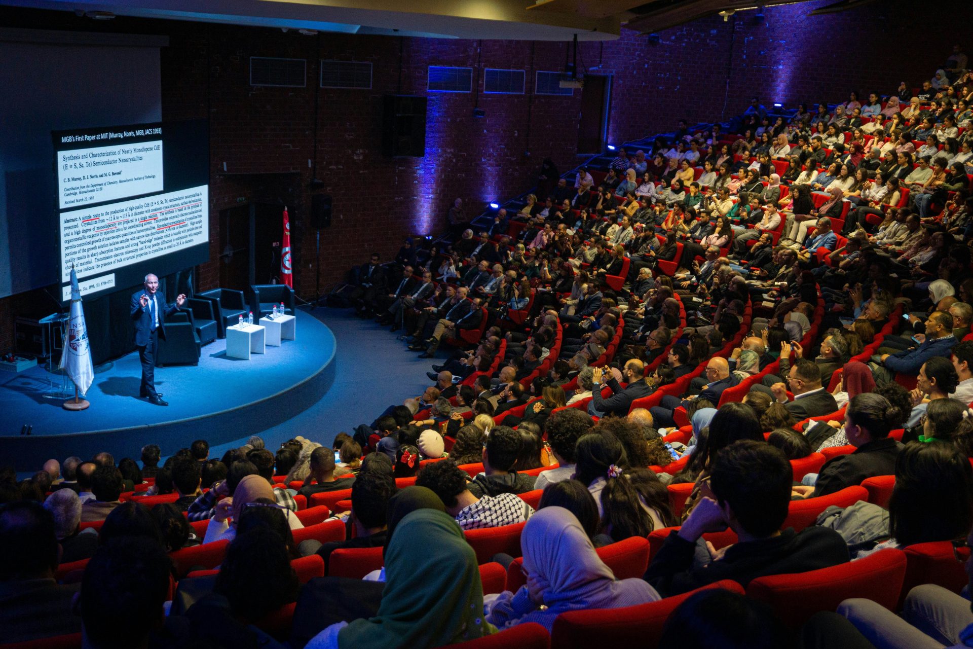 Speaker presenting to large audience in auditorium